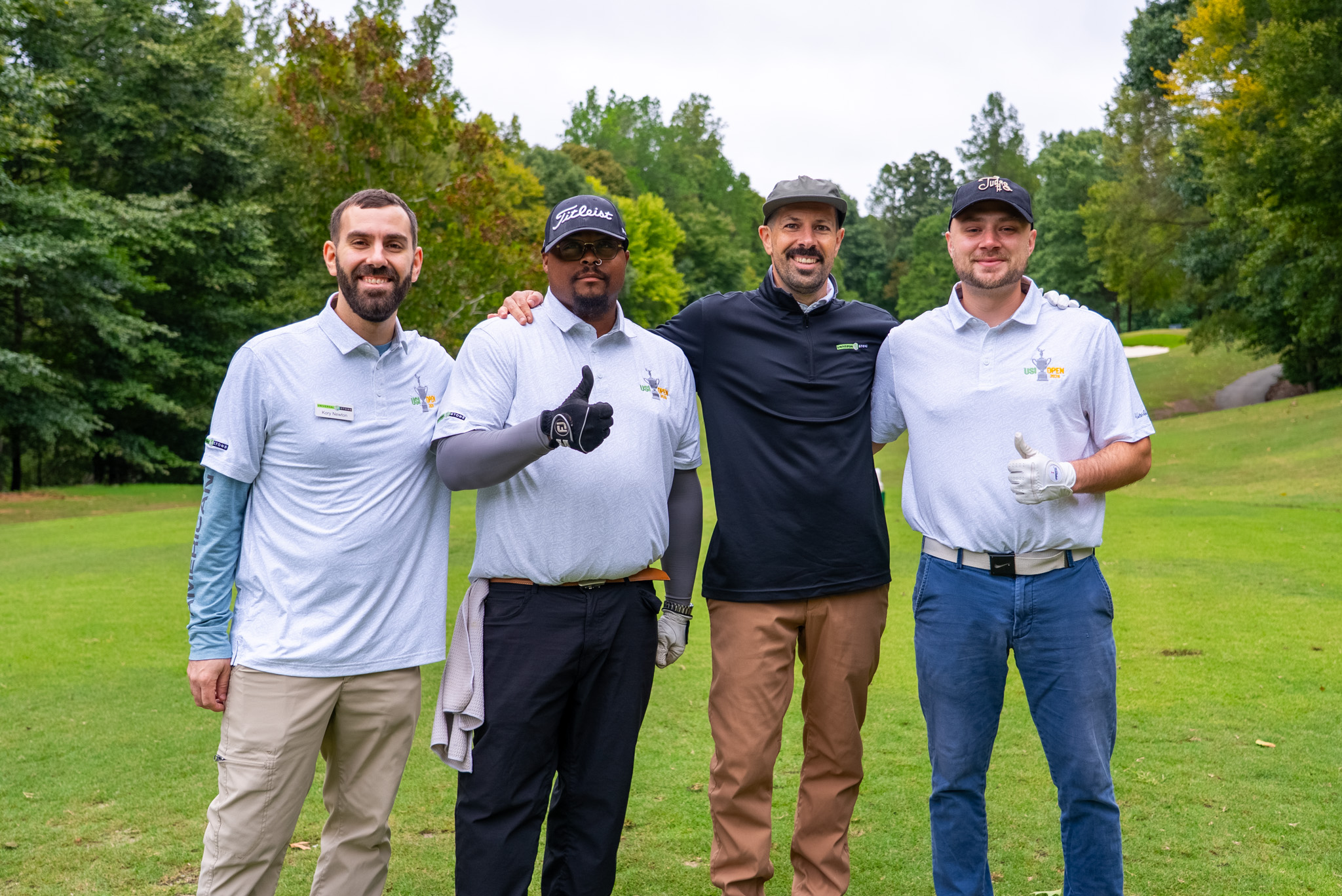 Energetic foursome in USI Open 2026 polos, arms around shoulders